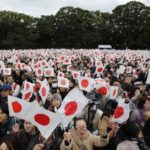 Well-wishers wave Japanese national flags to celebrate Japan’s Emperor Akihito’s 80th birthday at the Imperial Palace in Tokyo